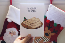 Person holding up a Christmas card with Mexican tamales on the cover.